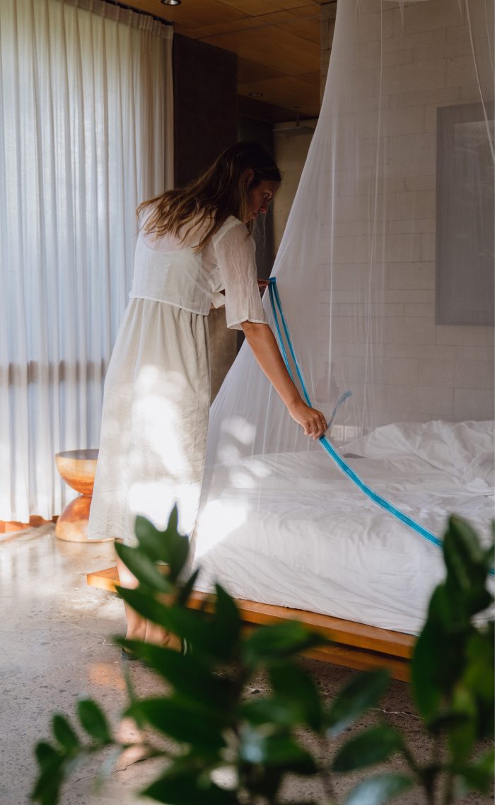 Frau öffnet Moskitonetz mit Reißverschluss